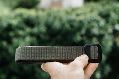 Yeşil doğal arka plana karşı el ele tutuşan adam yeni sürtünme kemeri renginde. 