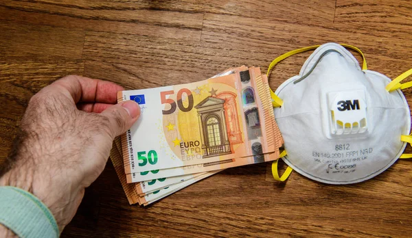 Homme payant des milliers d'euros de billets de banque pour la construction industrielle FFP2 — Photo