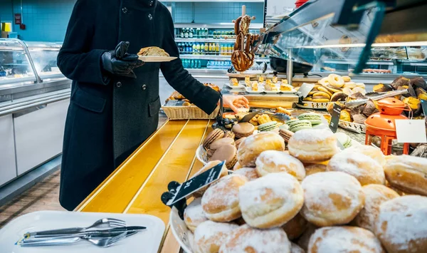 Vista laterale di una donna elegante in cappotto nero presa dal food court — Foto Stock