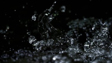 Suyun siyah arkaplana sıçrayan yüksek hızlı bulanık görüntüleri maden, soda, tonik ya da karbonat içeceklerinin ya da içeceklerin doğasından ferahlama kavramını temsil eder.