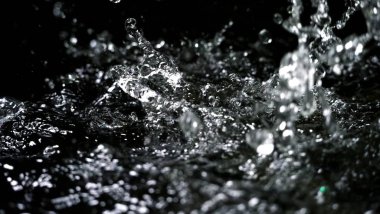 Suyun siyah arkaplana sıçrayan yüksek hızlı bulanık görüntüleri maden, soda, tonik ya da karbonat içeceklerinin ya da içeceklerin doğasından ferahlama kavramını temsil eder.