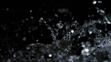 Suyun siyah arkaplana sıçrayan yüksek hızlı bulanık görüntüleri maden, soda, tonik ya da karbonat içeceklerinin ya da içeceklerin doğasından ferahlama kavramını temsil eder.