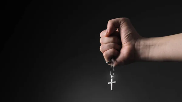 Imagens de close-up de pingente crucifixo e colar na mão sobre fundo de cor preta no estúdio que representam rezar por Deus ou Jesus e agradecer a Deus por dar pacífico e fiel às pessoas — Fotografia de Stock