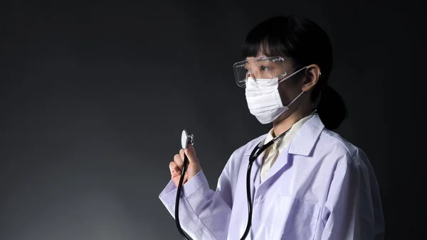 Asia young woman doctor with virus protector mask and glasses in studio black color background which represent about coronavirus outbreak that pandemic in Wuhan district of China and many people infected.