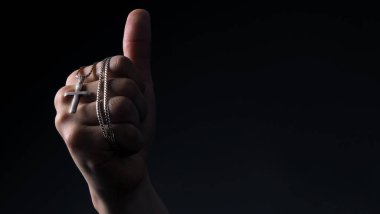 Stüdyoda, Tanrı 'ya ya ya da İsa' ya dua etmeyi temsil eden ve insanlara barışçıl ve sadık oldukları için Tanrı 'ya şükreden insan eliyle yapılan haç kolyesinin yakın plan görüntüleri.