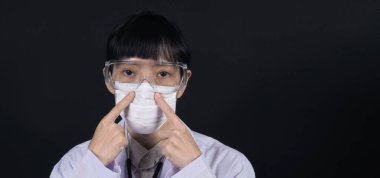 Tehlikeli koronavirüsü ya da Wuhan Çin 'den gelen covid-19 salgınını önleyen ve 2.5 gibi kötü kirliliği önleyen tıbbi maske takan Asyalı kadın doktor. 