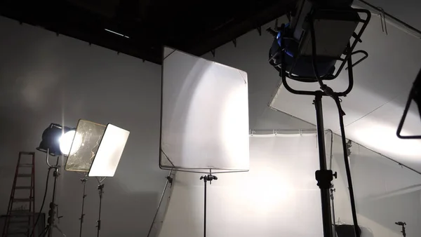 三脚や紙の背景に懐中電灯や継続的な照明を含む写真やビデオ制作を撮影するために設定され 写真家やビデオカメラマンのために使用されるスタジオライトとバックドロップとソフトボックス — ストック写真