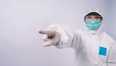 PPE kostümlü ya da Kişisel Koruma Ekipmanı 'ndaki doktor, salgın virüsünü korumak ve mücadele etmek için beyaz renkli tıbbi lastik eldivenler, temiz gözlükler ve yeşil N95 maskesi taktığını belirtiyor.