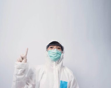 PPE kostümlü ya da Kişisel Koruma Ekipmanı 'ndaki doktor, salgın virüsünü korumak ve mücadele etmek için beyaz renkli tıbbi lastik eldivenler, temiz gözlükler ve yeşil N95 maskesi taktığını belirtiyor.