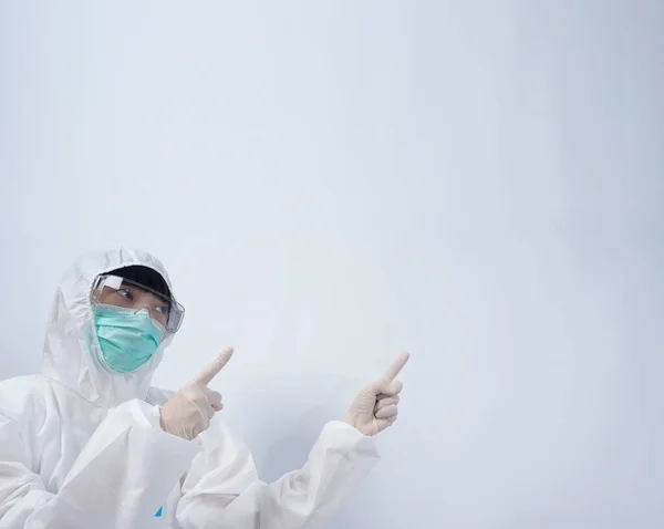 Doctor in PPE suit or Personal Protection Equipment point out to copy space and wearing white color medical rubber gloves and clear goggles glasses and green N95 mask to protect and fight pandemic virus