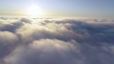 Hava görüntüsü. Sisin içinde uçmak, sisin içinde uçmak. Hava kamerası görüntüsü. Bulutların üzerinden güneşe doğru uç. Sisli hava, yukarıdan manzara.