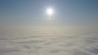 Hava görüntüsü. Sisin içinde uçmak, sisin içinde uçmak. Hava kamerası görüntüsü. Bulutların üzerinden güneşe doğru uç. Sisli hava, yukarıdan manzara.