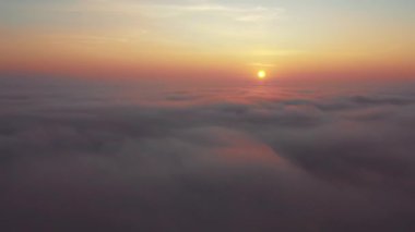 Hava görüntüsü. Sisin içinde uçmak, sisin içinde uçmak. Hava kamerası görüntüsü. Bulutların üzerinden güneşe doğru uç. Sisli hava, yukarıdan manzara.