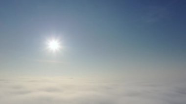Hava görüntüsü. Sisin içinde uçmak, sisin içinde uçmak. Hava kamerası görüntüsü. Bulutların üzerinden güneşe doğru uç. Sisli hava, yukarıdan manzara.