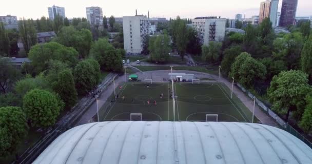 Aerial view of football pitch at night with amateur football players playing the game in the city. — Stock Video