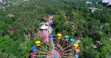 Underside or side view from ground of a ferris wheel over blue sky. Bright and colorful fragment of moving round ferris wheel in summer. 4K