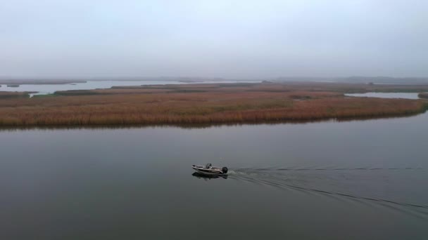 Los pescadores a caballo barco azul para la pesca en la niebla de la mañana. Vista de las casas tradicionales de pescadores construidos con bambú en el mar en la desembocadura del río antes de entrar en el gran mar . — Vídeos de Stock