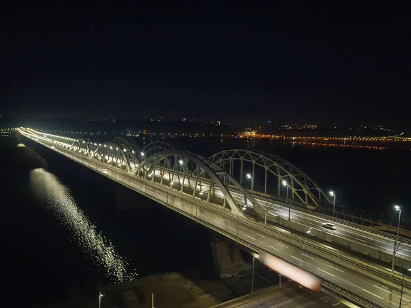 Gece şehrinin fenerle aydınlatılmış köprüsünde yoğun bir trafik var.. — Stok fotoğraf