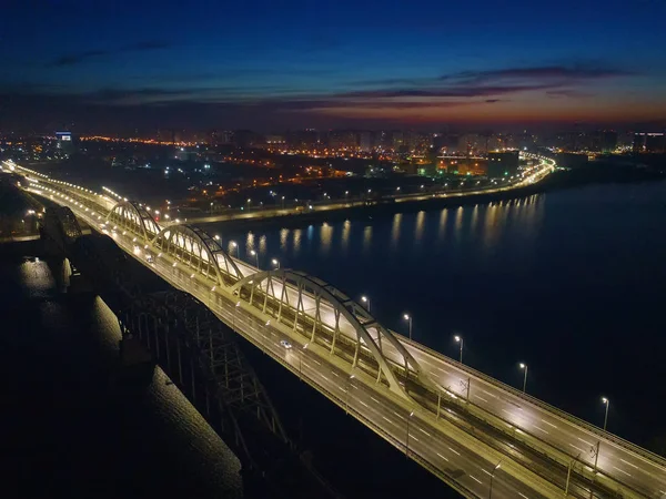 Tráfico ocupado en el puente iluminado por linternas de la ciudad nocturna . — Foto de Stock