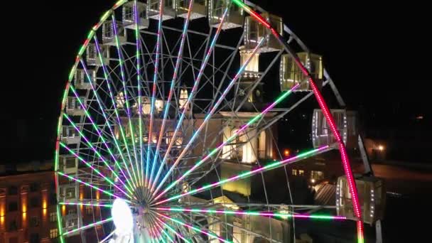 Hell erleuchtetes Riesenrad, das sich nachts in einem Karneval, Vergnügungspark, Freizeitpark, Jahrmarkt, Nervenkitzelpark dreht. — Stockvideo