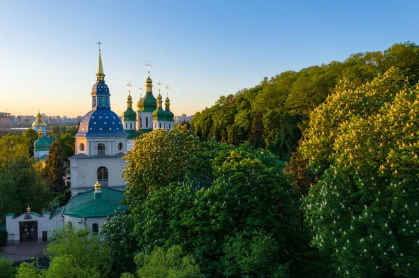 Golden and green domes of orthodox church in the middle of autumn park. Famous building is blurred. — Stock Photo, Image