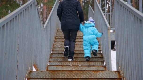 젊은 어머니와 그녀의 작은 아이가 계단을 걷고 있다 — 비디오