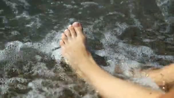 Πόδια που βρέχεται από θαλασσινό νερό. Πολλά πόδια πάνω στην αμμώδη παραλία. Κύματα ροή κάτω από τα πόδια. Τα νύχια σε θαλασσινό νερό. — Αρχείο Βίντεο