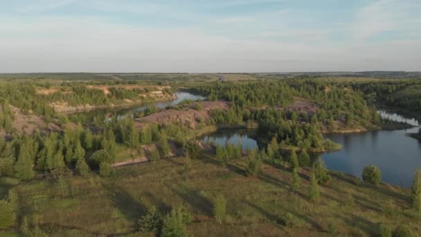 Drone vliegen over een klein meer omgeven door schaarse vegetatie met blauwe luchten en witte wolken — Stockvideo