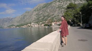 Kadın gezgin Kotor körfezi boyunca yürüyor ve güzel bir manzaranın tadını çıkarıyor. Kotor Montenegr