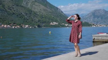 Kadın gezgin Kotor körfezi boyunca yürüyor ve güzel bir manzaranın tadını çıkarıyor. Kotor Montenegr