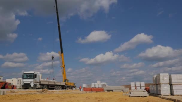 La descarga de ladrillos en una obra de construcción utilizando una grúa y los trabajadores. Trabajos de montaje sobre el movimiento de materiales de construcción en un día soleado de verano. Construcción del Timelapse — Vídeo de stock