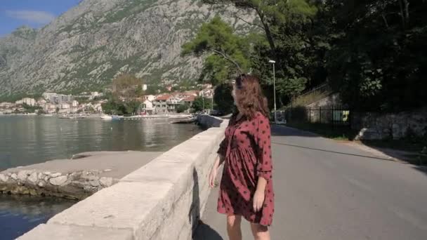 Kobieta spaceruje wzdłuż zatoki Kotor promenady i cieszy się pięknym widokiem. Kotor Czarnogóra — Wideo stockowe