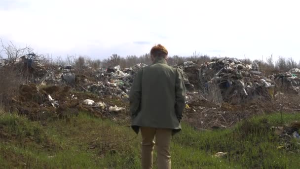 의료용 마스크를 쓴 젊은 남자가 매립지 근처를 걷고 있어요. 생태계 의대 재난 — 비디오