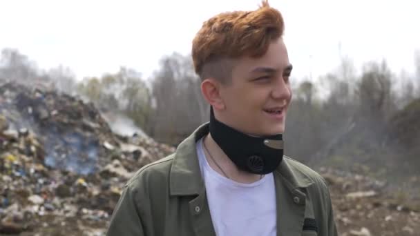 Retrato de un chico joven mira a la cámara en un enorme fondo de relleno sanitario de plástico. Catástrofe ecológica — Vídeos de Stock