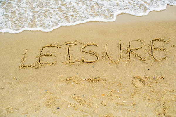 ビーチの砂の上に書かれた単語レジャー — ストック写真