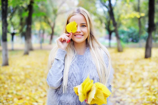 Mujer sosteniendo racimo de hojas amarillas de otoño — Foto de Stock