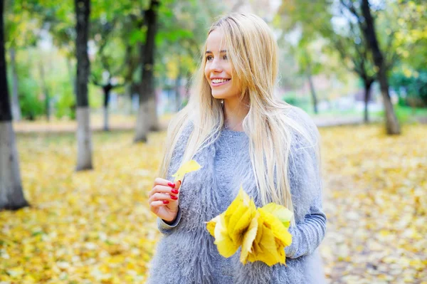 Mujer sosteniendo racimo de hojas amarillas de otoño — Foto de Stock