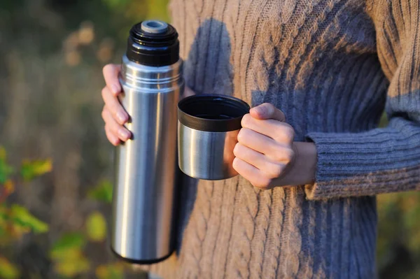 Hands holding thermos cup and bottle