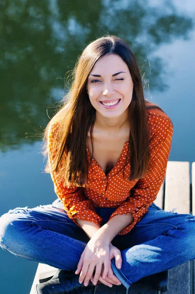 Hermosa joven sentada en el borde del embarcadero de madera — Foto de Stock