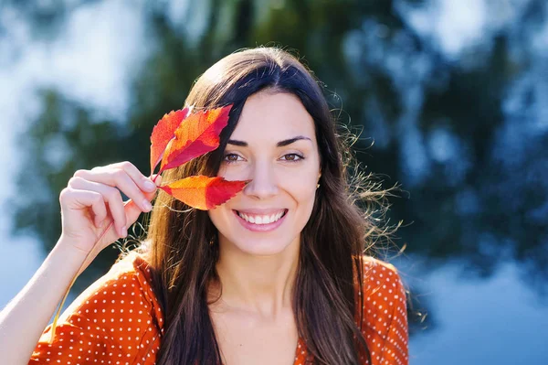 Hermosa joven sonriente con hoja roja de otoño — Foto de Stock