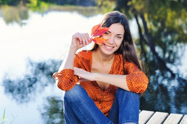 Hermosa joven sonriente con hoja roja de otoño — Foto de Stock