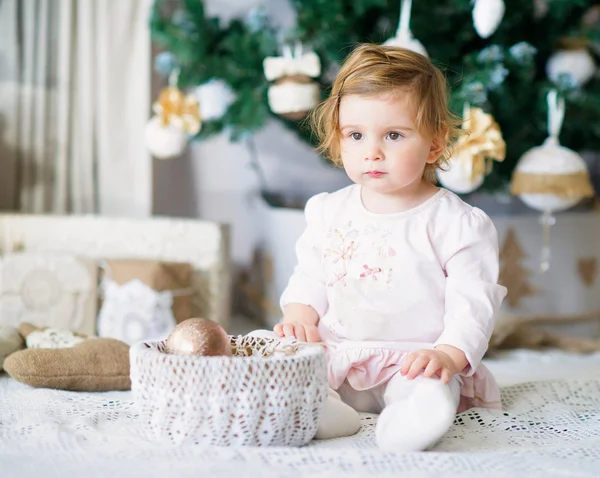 Schattig klein meisje door de kerstboom — Stockfoto