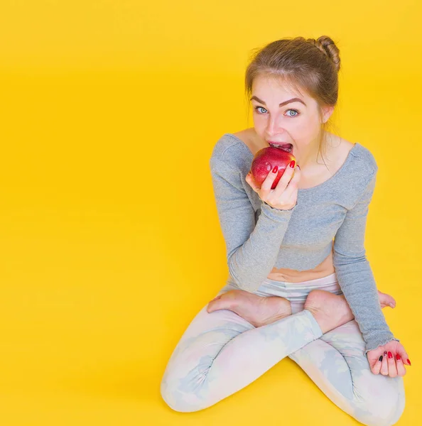 Girl in lotus pose eating apple — Stock Photo, Image