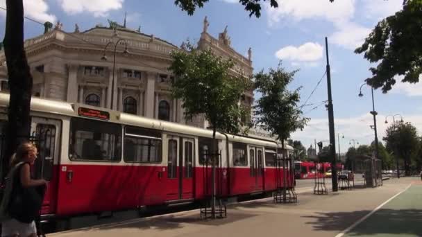 VIENNA, AUSTRIA- MAY 16: Ringstrasse is one of the main streets with The Burgtheater and red tram. Vienna is the number one city in the world in "Quality of Living" survey of hundreds of cities. — Stock Video