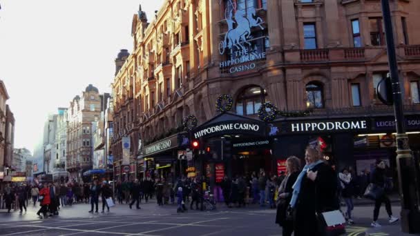 London, Wielka Brytania. Grudnia 21. Na skrzyżowaniu Charing Cross Road i Cranbourn Street, dokładnie naprzeciwko Leicester Square. Ludzie chodzą ulicą w sunset.ultra hd 4k — Wideo stockowe