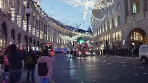 Londra - Aralık 19: Noel ışıkları ekran Regent Caddesi üzerinde Aralık 19, Londra, İngiltere. Modern renkli Noel ışıkları çekmek ve insanlar sokaklarda teşvik. — Stok video