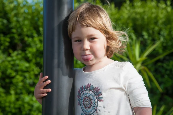 Маленький ребенок торчит язык в саду — стоковое фото