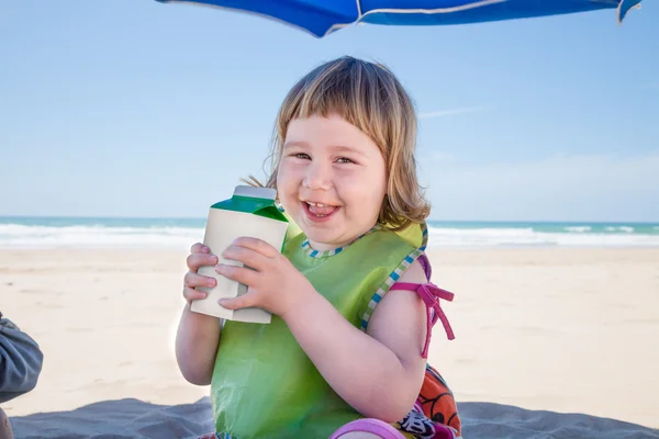 Criança pequena com recipiente de bebidas nas mãos na praia — Fotografia de Stock