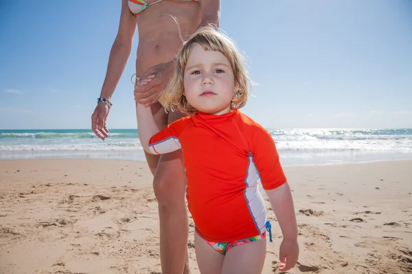 Tittar litet barn som håller hand mor på stranden — Stockfoto