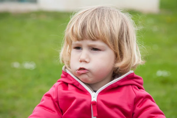 Baby in red portrait chewing in park — Stock Photo, Image